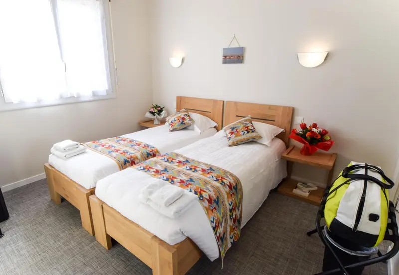 Une chambre lumineuse avec deux lits simples et une décoration florale.