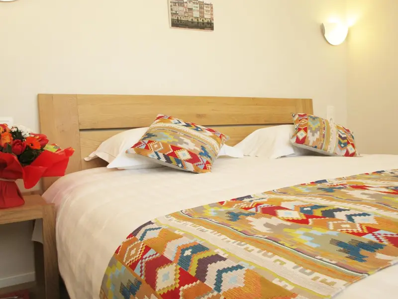Une chambre lumineuse avec un grand lit décoré de coussins colorés et d'une courtepointe.