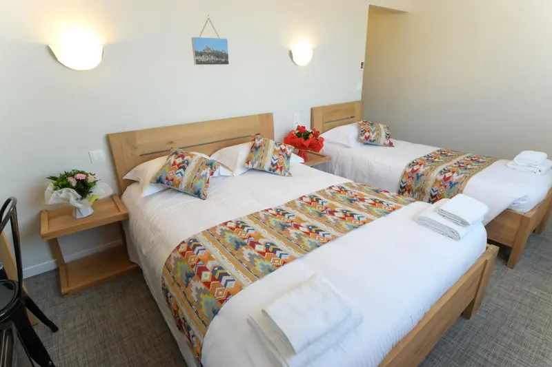 Une chambre lumineuse avec deux lits simples décorés de coussins colorés.