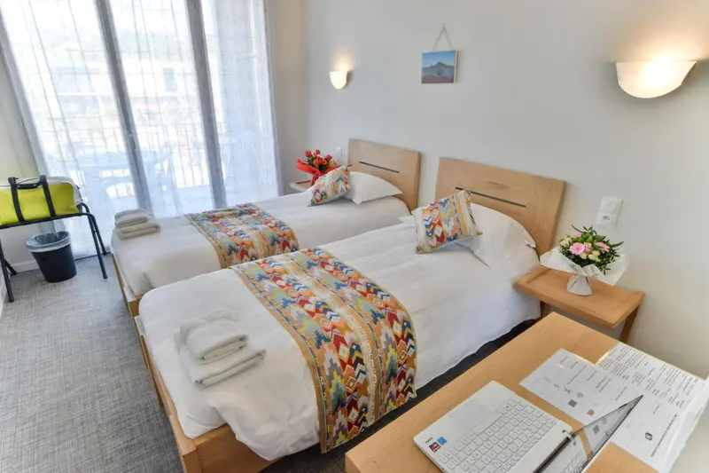 Une chambre lumineuse avec deux lits simples et une vue sur l'extérieur.