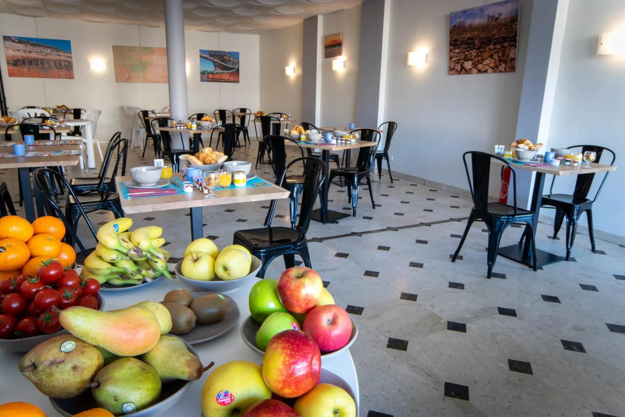 Une salle lumineuse avec des tables et des chaises où les clients prennent leur petit-déjeuner.