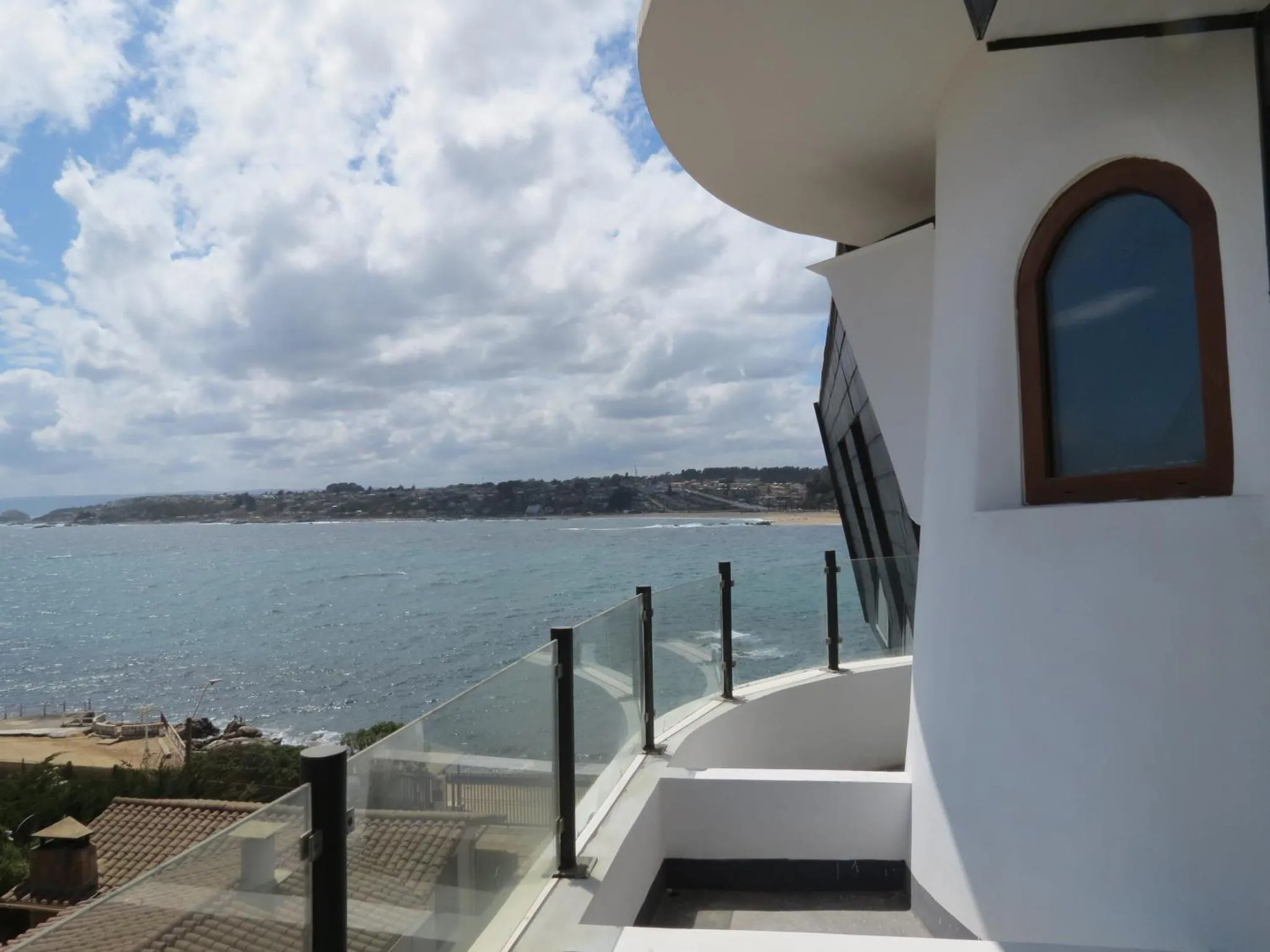 Vue d'une terrasse avec une rambarde en verre donnant sur la mer et la côte.