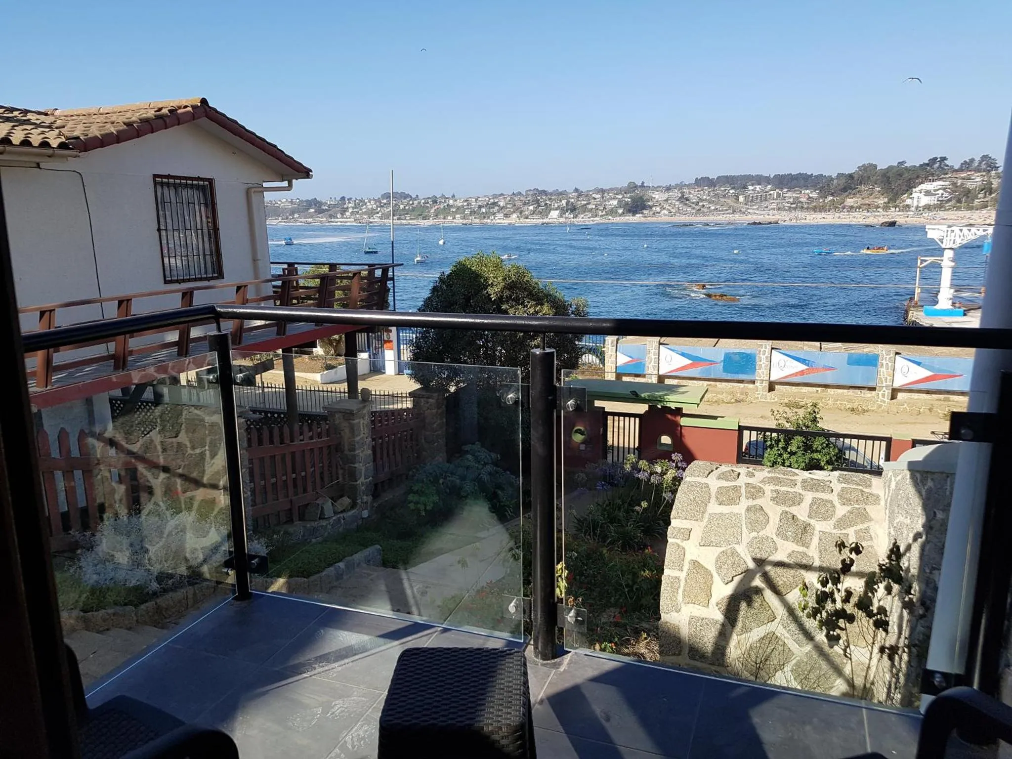 Vue d'une terrasse avec une rambarde en verre donnant sur la mer et la côte.