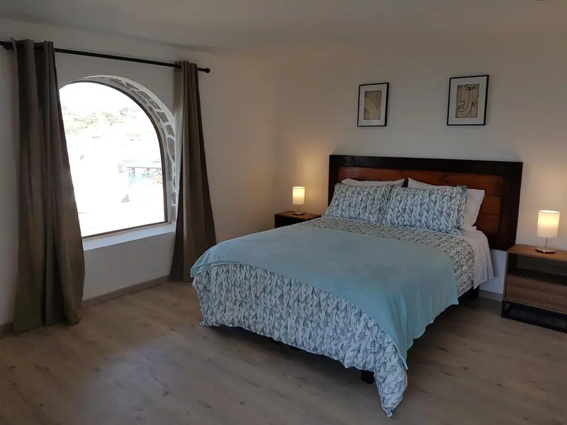 Une chambre lumineuse avec un grand lit recouvert d'une couette.