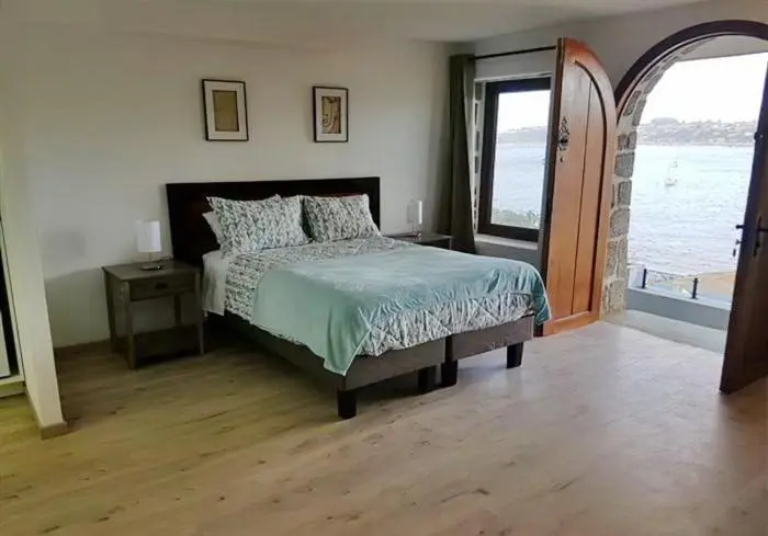 Une chambre lumineuse avec un lit fait et une vue sur la mer.