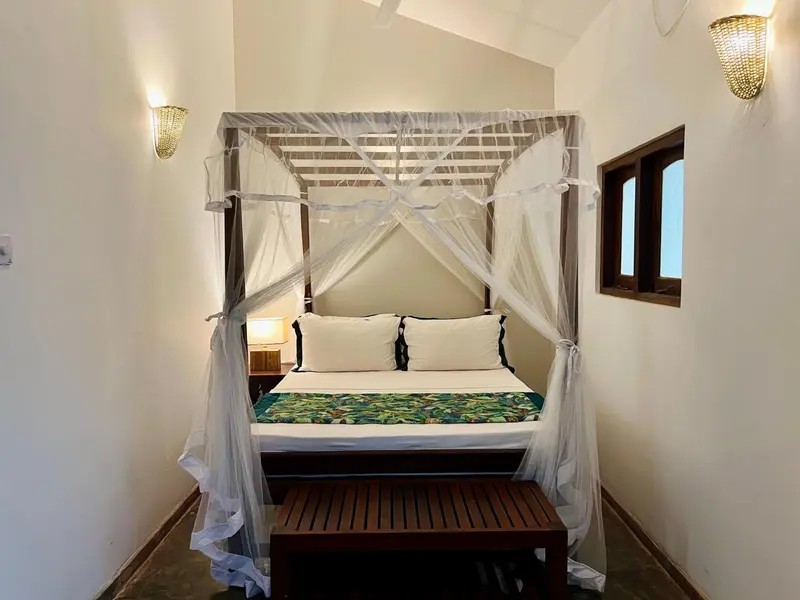 Une chambre lumineuse avec un lit à baldaquin et une décoration sobre.