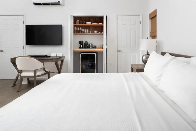 Une chambre lumineuse avec un lit fait et un espace bureau.