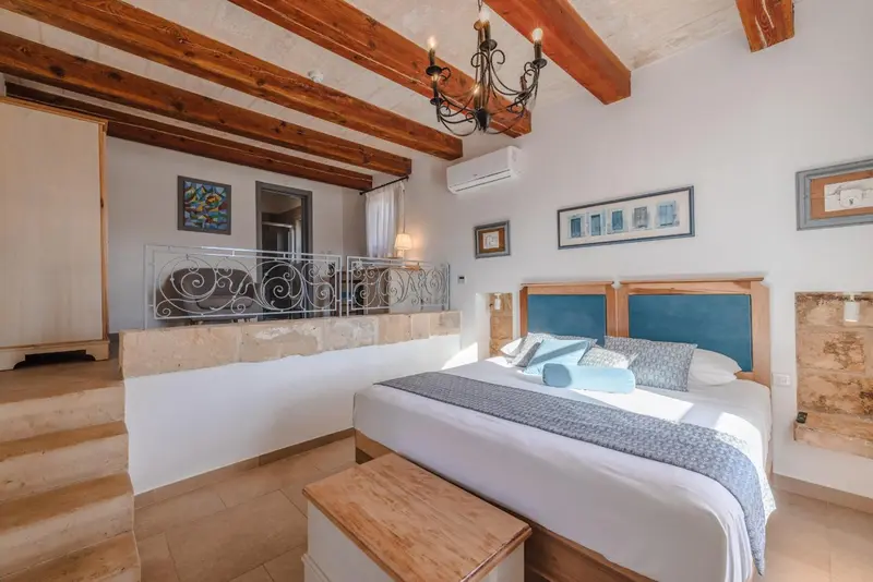 Une chambre lumineuse avec un lit recouvert d'une courtepointe et un balcon en fer forgé.