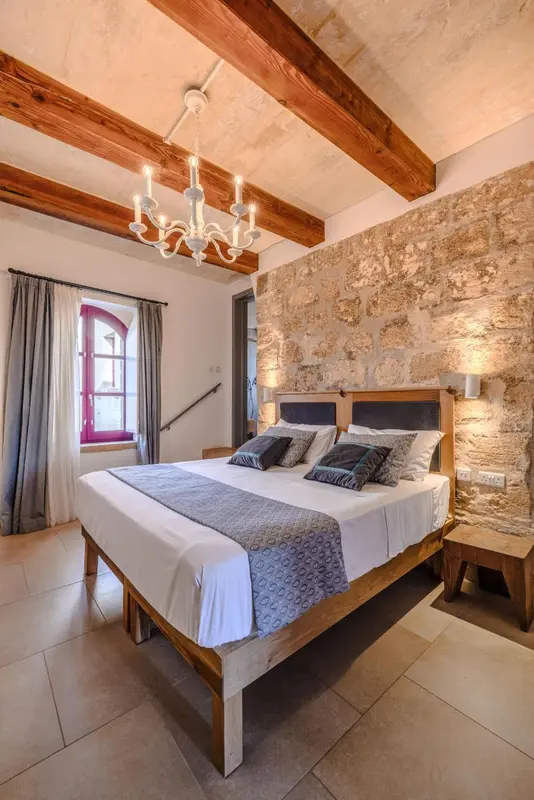 Une chambre à coucher lumineuse avec un lit à baldaquin et des murs en pierre.