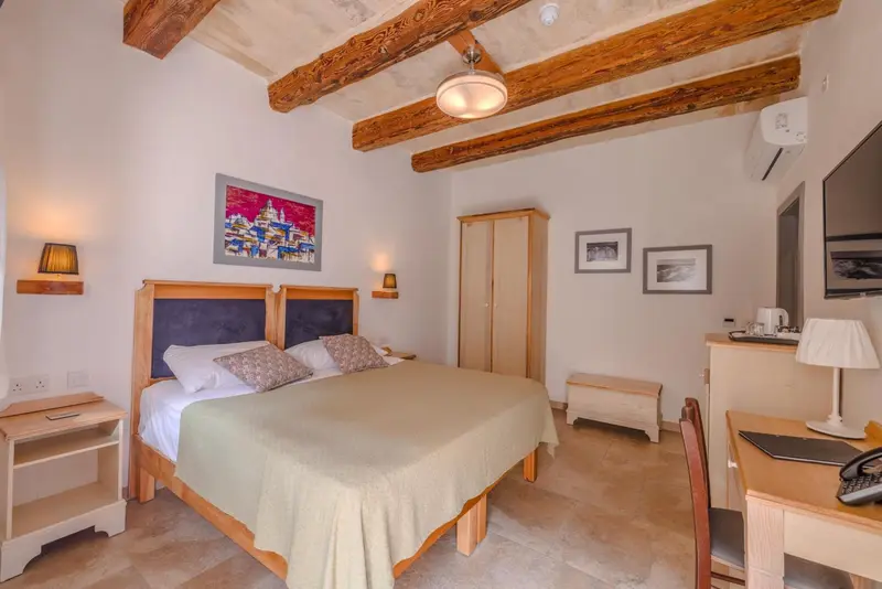 Une chambre lumineuse avec un lit double et des meubles en bois.