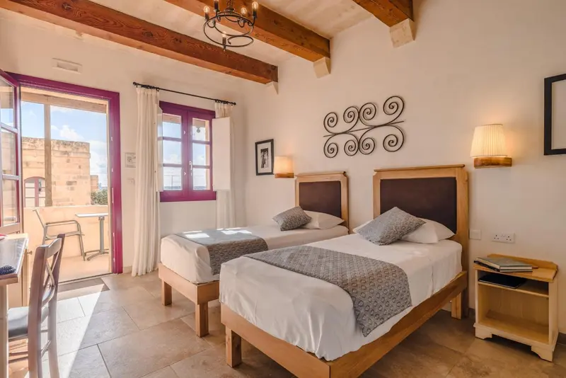 Chambre lumineuse avec deux lits simples et balcon.