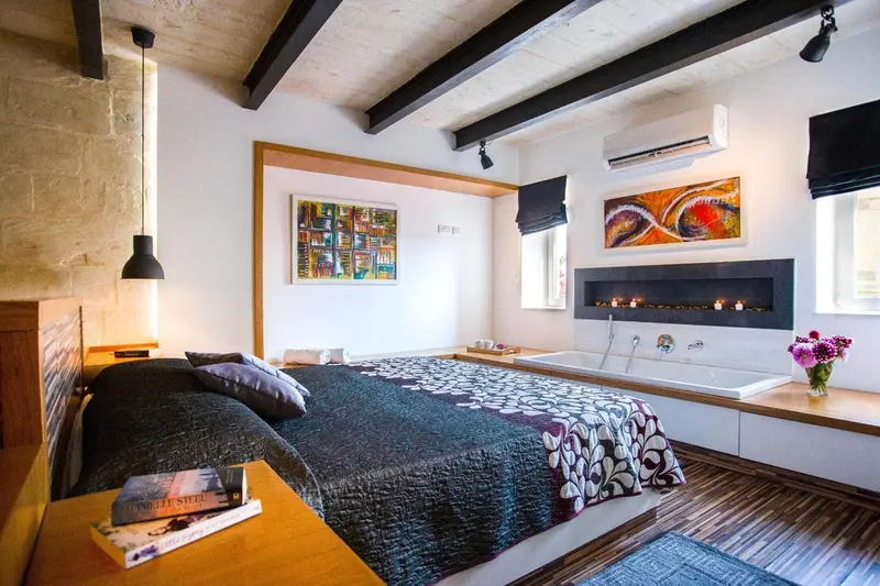 Une chambre à coucher avec un grand lit et une baignoire intégrée.