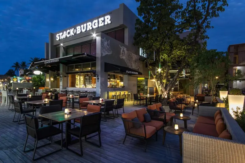 Terrasse lumineuse avec tables et canapés devant un bâtiment moderne.