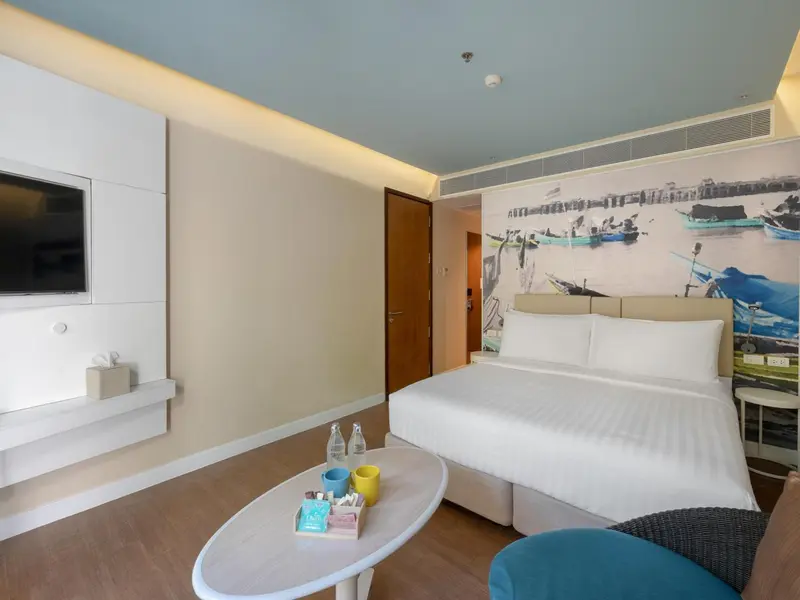 Une chambre lumineuse avec un grand lit et une décoration murale représentant des bateaux.