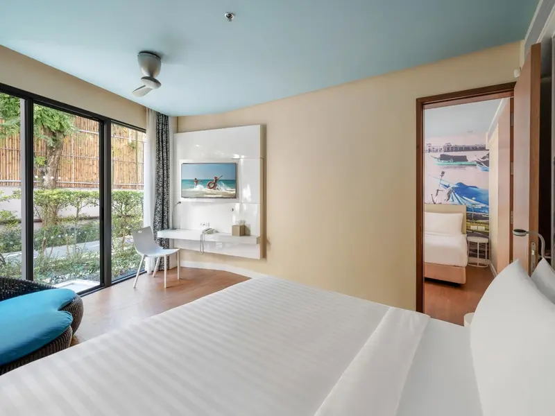 Une chambre lumineuse avec un grand lit et un accès à un espace extérieur végétal.