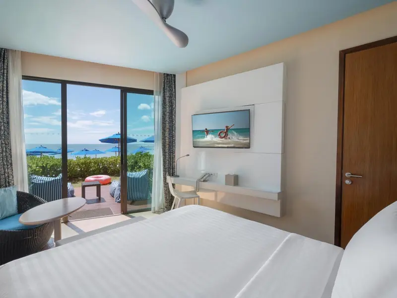 Une chambre lumineuse avec vue sur la mer et un balcon.