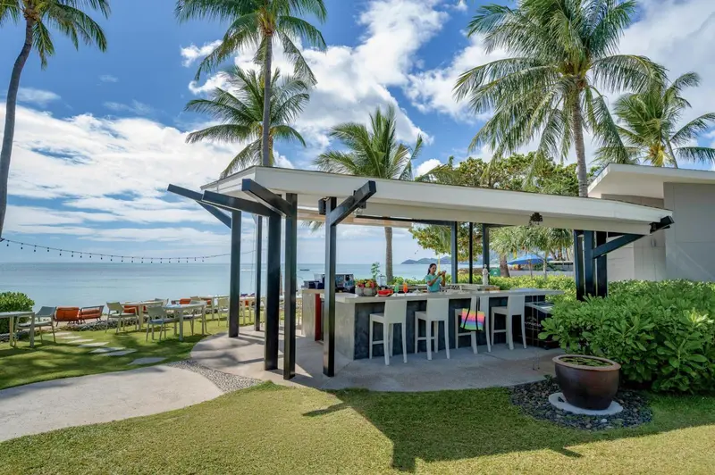 Un bar extérieur avec des tabourets et une vue sur la mer.
