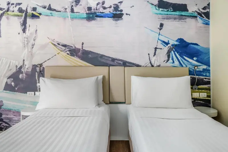 Une chambre avec deux lits simples et un mur décoré d'une fresque marine.