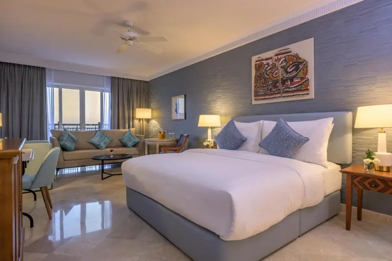 Une chambre lumineuse avec un grand lit et un coin salon.