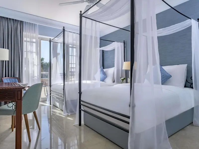 Une chambre lumineuse avec un lit à baldaquin et une vue sur l'extérieur.