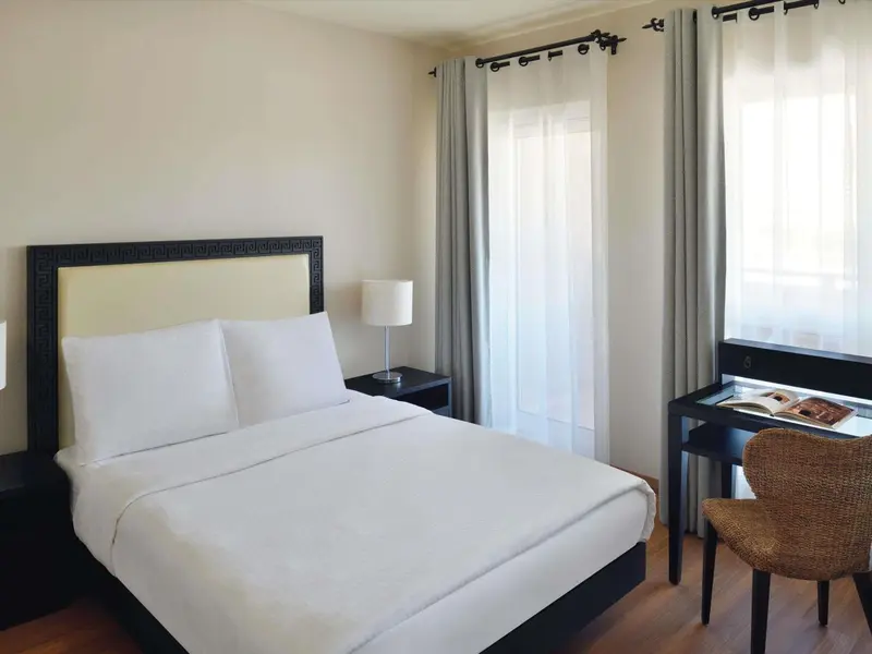 Une chambre lumineuse avec un grand lit et un bureau.