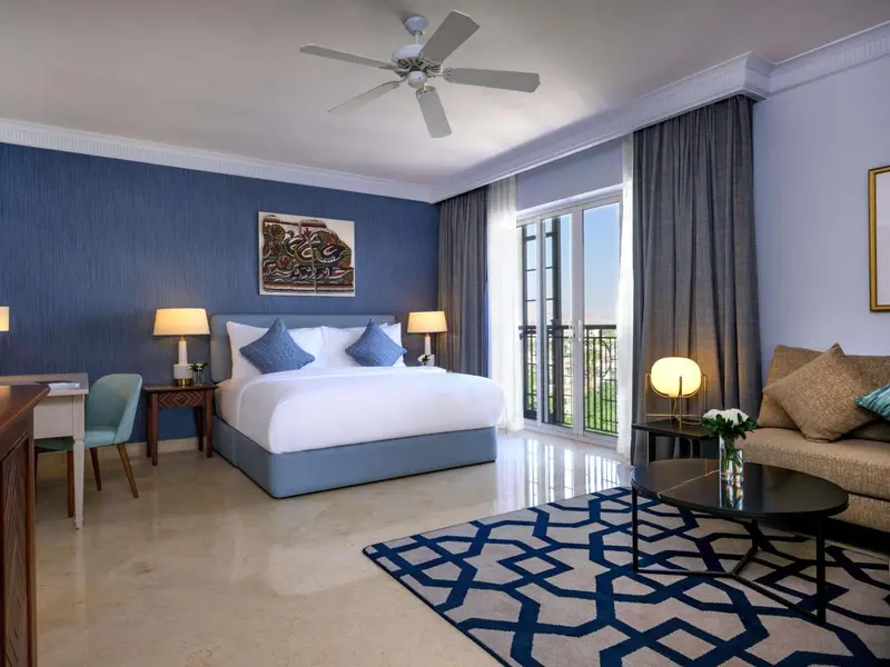 Une chambre lumineuse avec un grand lit et un espace salon.