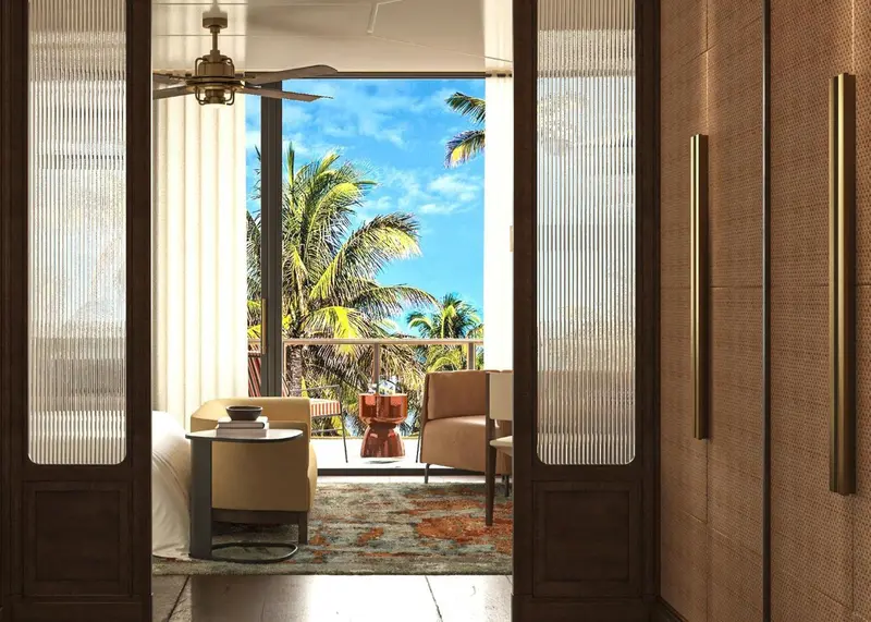 Une pièce lumineuse s'ouvre sur une vue tropicale avec des palmiers et une mer turquoise.