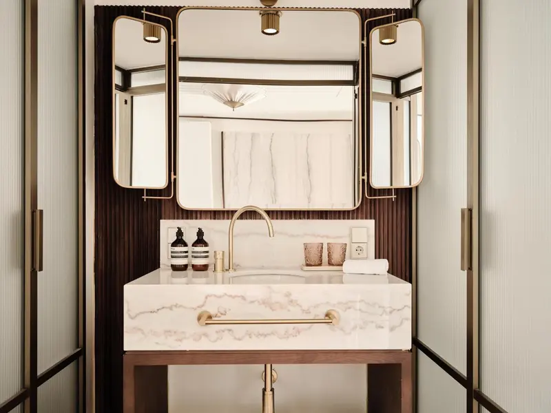 Une salle de bain moderne avec un lavabo en marbre et des miroirs encadrés.