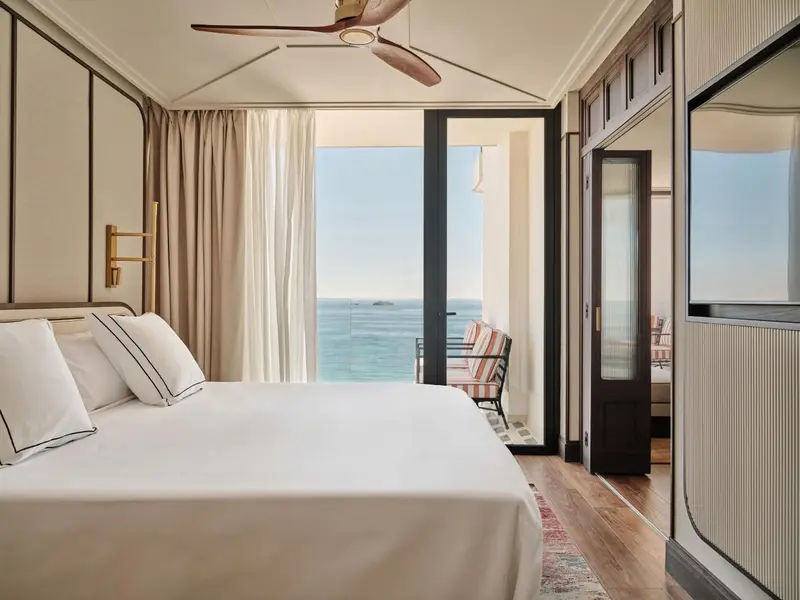 Une chambre lumineuse avec un lit fait face à une vue sur la mer.