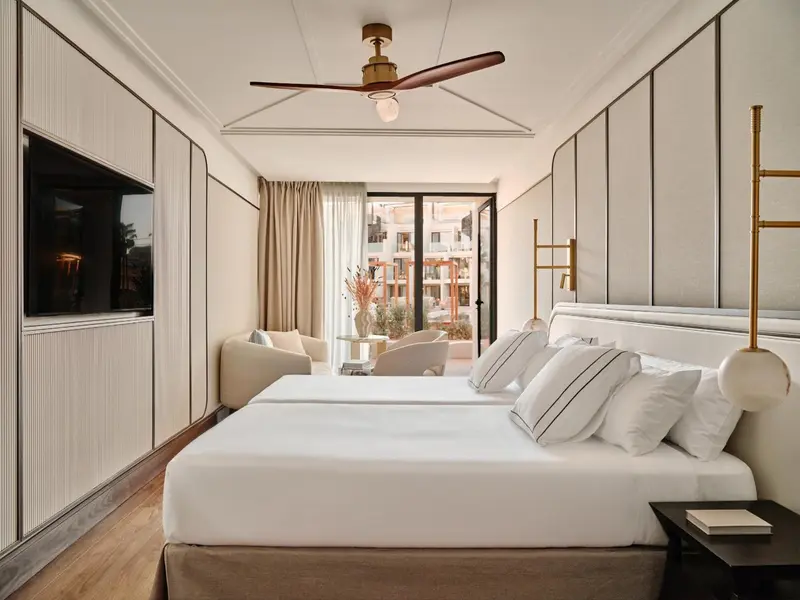 Chambre lumineuse avec un grand lit et une fenêtre donnant sur l'extérieur.