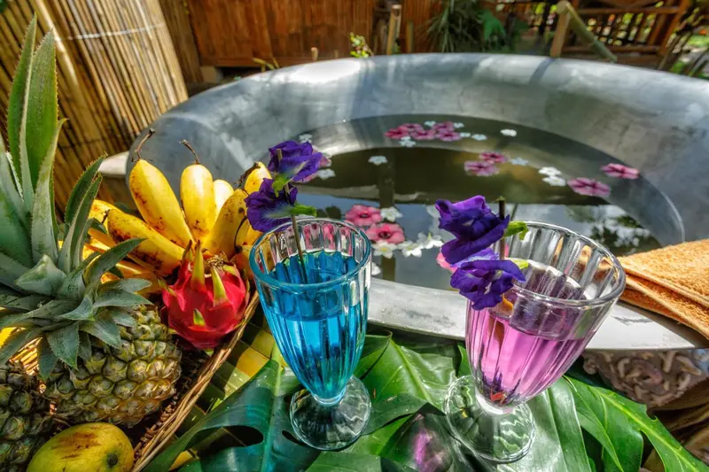 Nature morte tropicale avec des fruits, des fleurs et des boissons colorées.
