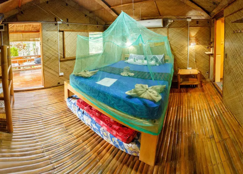 Une chambre lumineuse avec un lit recouvert d'une moustiquaire et un sol en bois.