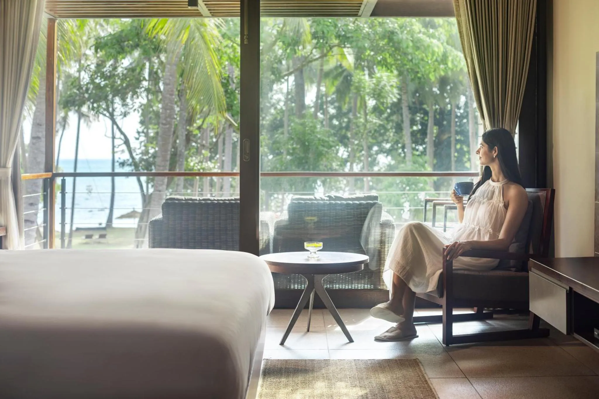 Une femme assise se détend dans un intérieur lumineux avec vue sur la mer.