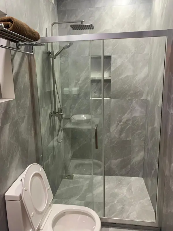 Une douche à l'italienne moderne avec des carreaux gris et des parois vitrées.