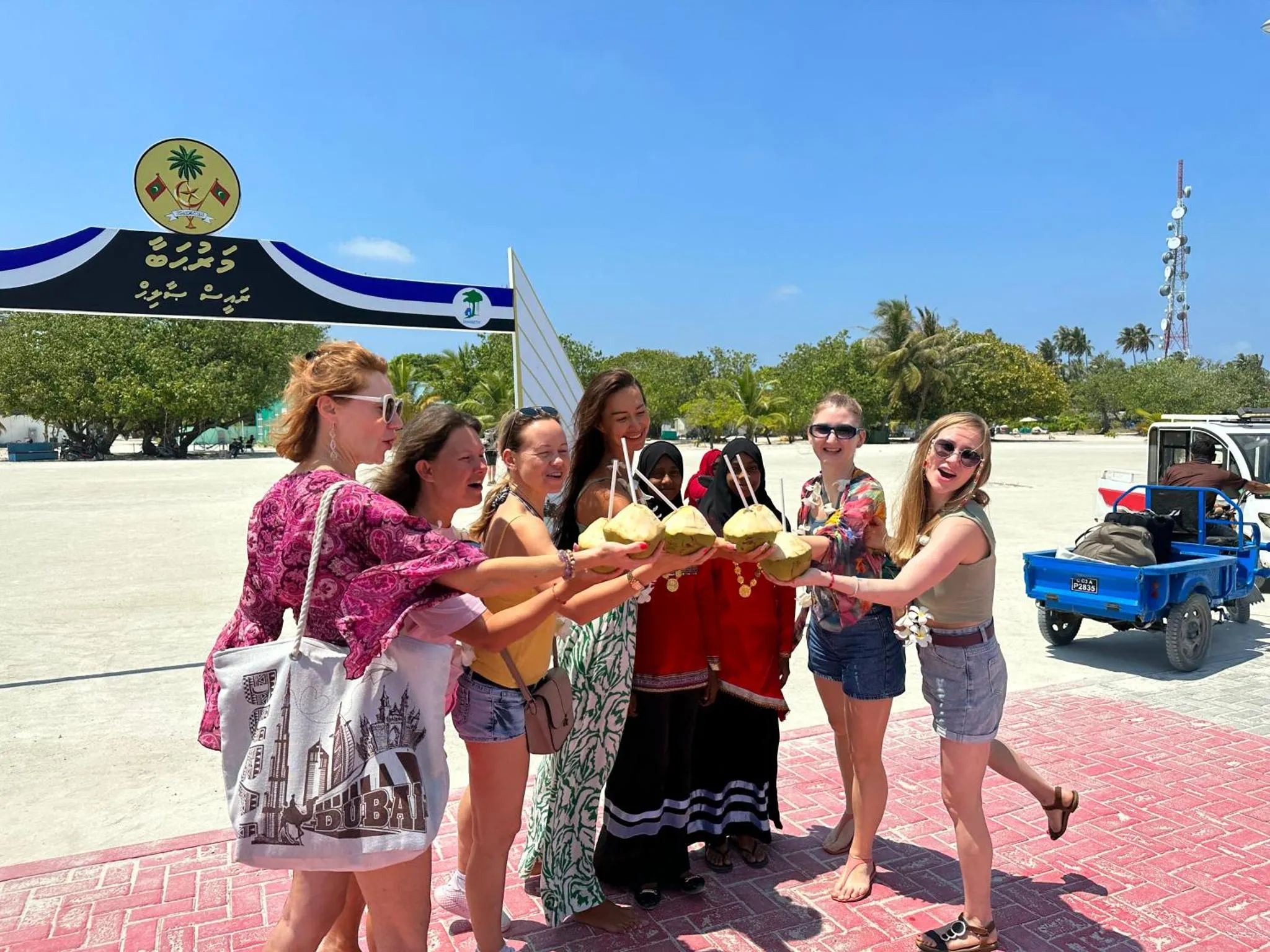 Un groupe de personnes se tient sur une plage de sable blanc et boit dans des noix de coco.