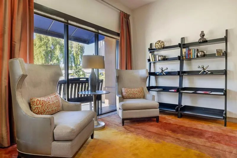 Un salon lumineux avec deux fauteuils confortables et une bibliothèque ouverte.