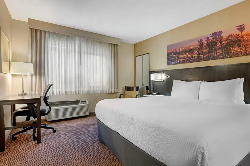 Une chambre d'hôtel lumineuse avec un grand lit et un bureau.