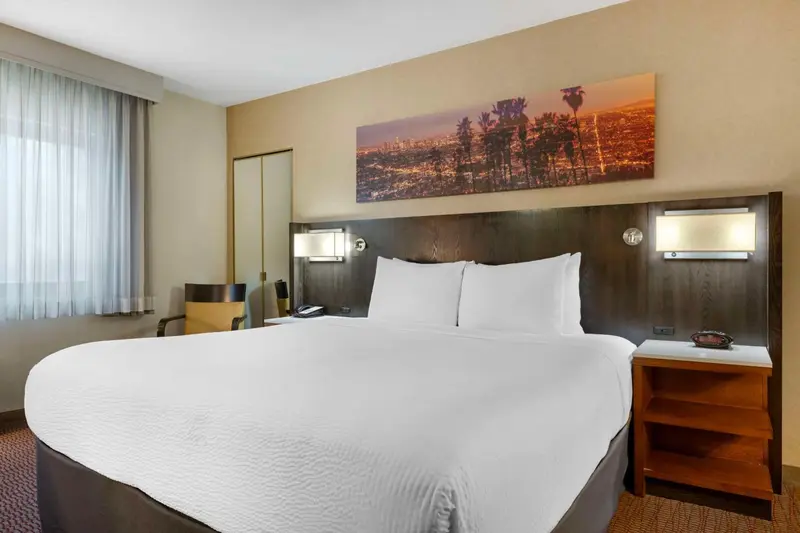 Une chambre d'hotel avec un grand lit et une décoration murale représentant une ville.