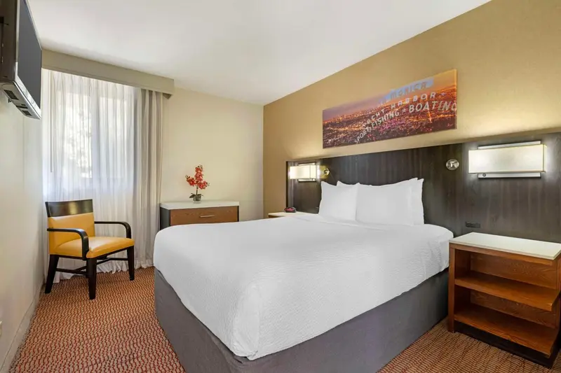 Une chambre d'hôtel lumineuse avec un grand lit et un fauteuil.