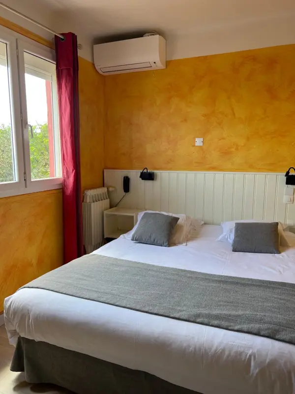 Une chambre lumineuse avec un lit double et une fenêtre.