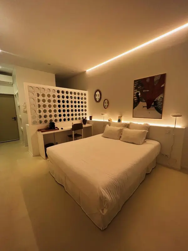 Une chambre lumineuse avec un grand lit recouvert d'une couette blanche.