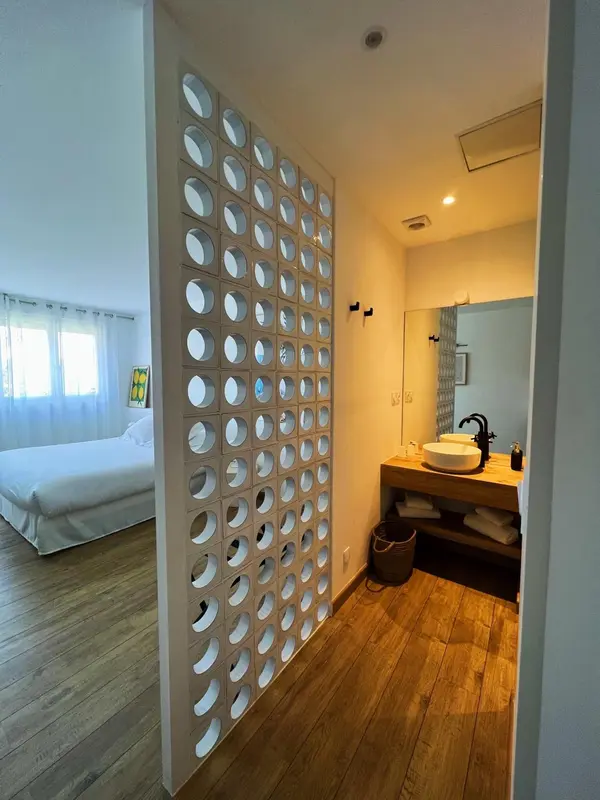 Une chambre lumineuse avec un espace lavabo et un mur ajouré.