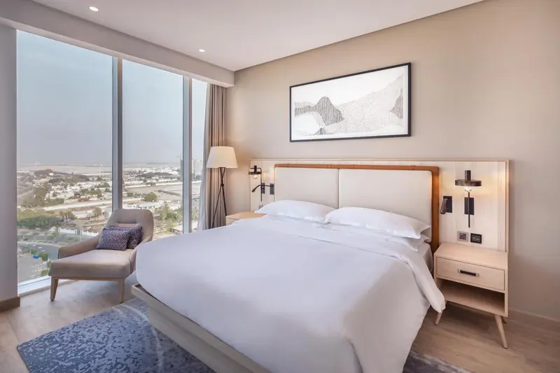 Une chambre lumineuse avec un grand lit et une vue sur la ville.