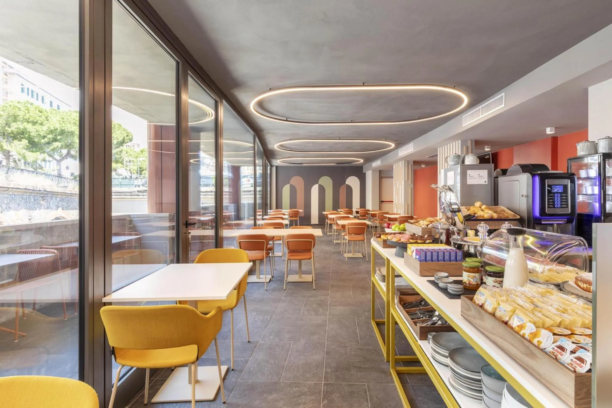 Une salle lumineuse avec des tables et des chaises, un buffet de nourriture et des boissons.