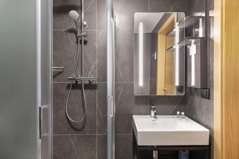 Une douche à l'italienne moderne avec un grand miroir éclairé.