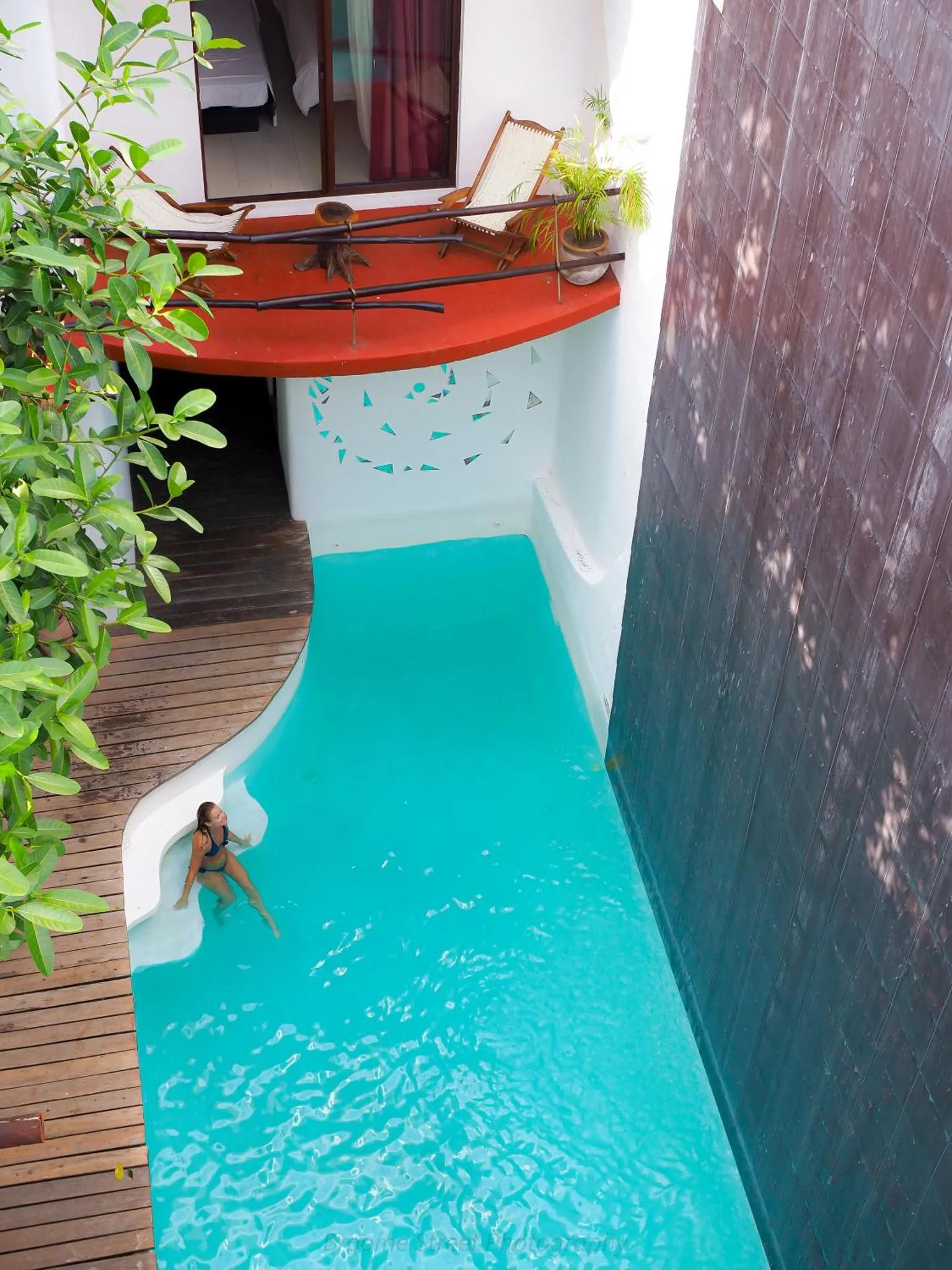 Une femme se détend dans une piscine turquoise étroite et allongée.