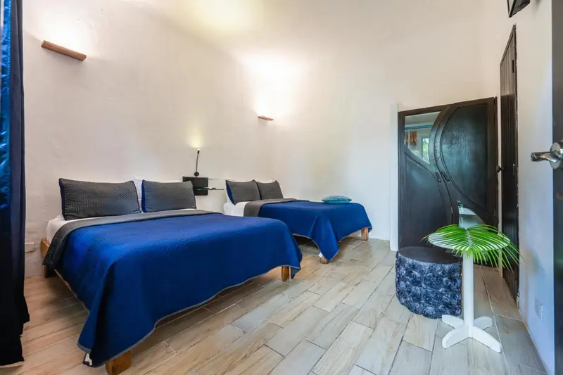 Une chambre lumineuse avec deux lits simples recouverts de couvertures bleues.