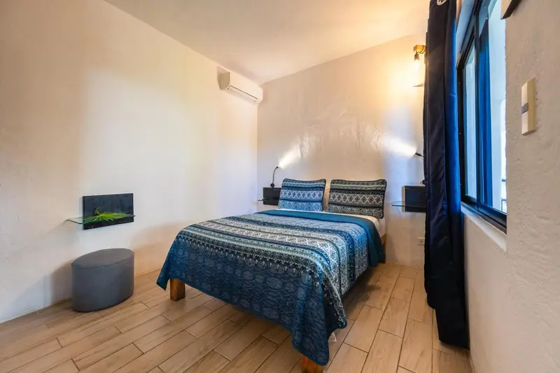 Une chambre lumineuse avec un lit double et un aquarium.