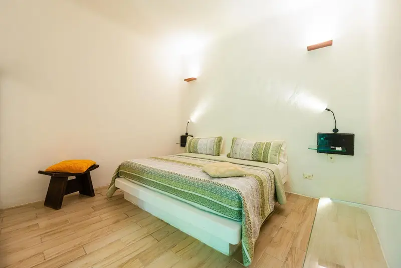 Une chambre lumineuse avec un grand lit et des coussins décoratifs.