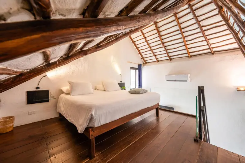 Une chambre mansardée avec un lit double et un parquet en bois.